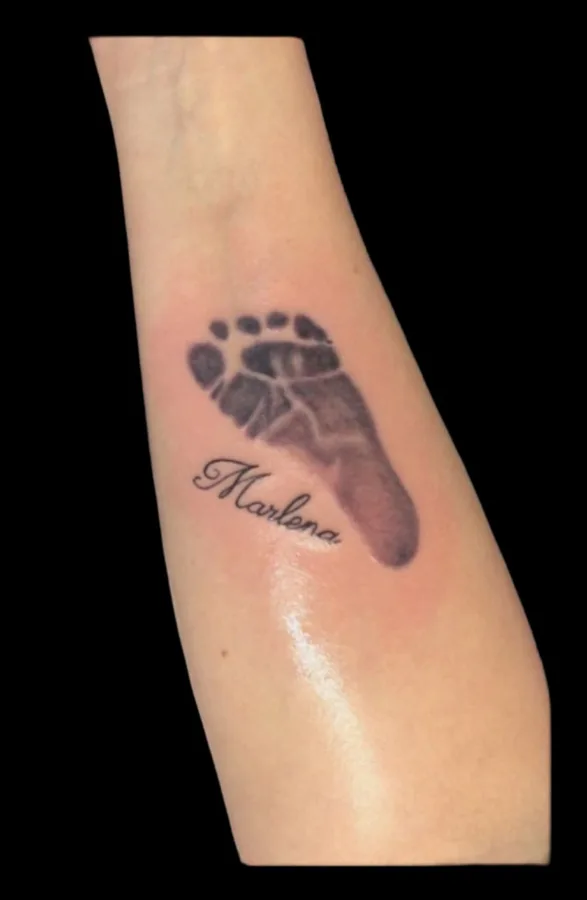 Tattoo eines Babyfuss-Abdrucks mit Namen am Unterarm, SkinLove Marchtrenk