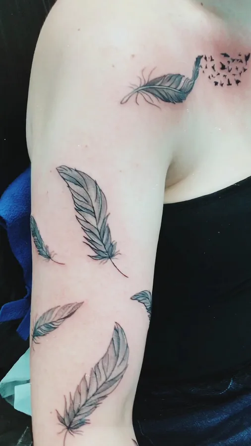 Federn-Tattoo mit aufsteigenden Vögeln über Schulter und Oberarm, SkinLove Marchtrenk